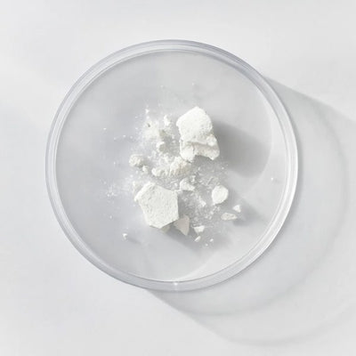 White powdery substance in a clear glass container on a light gray background